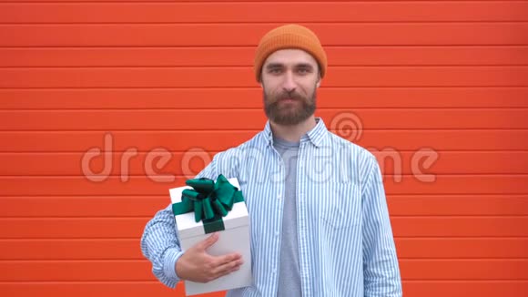 英俊的年轻臀部拿着红色背景的礼品盒节日和生日的概念视频的预览图