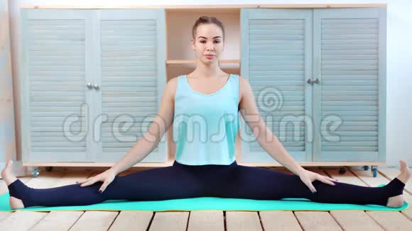 自信地伸展年轻女子坐在垫子上用麻绳全射练习瑜伽视频的预览图