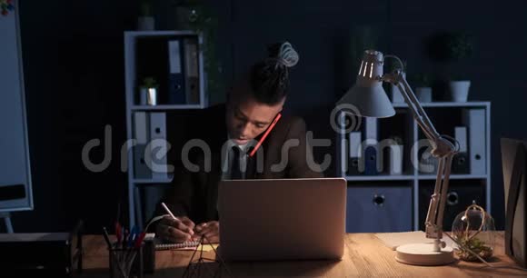 在夜间办公的时候商人在用手机做笔记视频的预览图