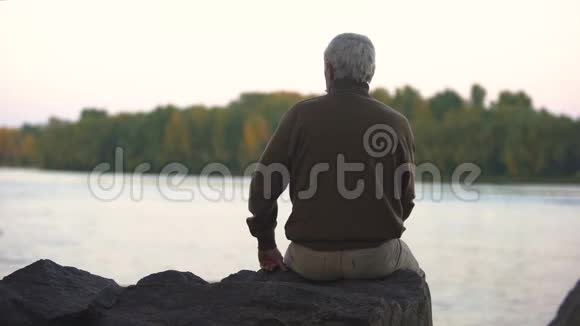 伤心的爷爷坐在河岸后景晚年寂寞安息视频的预览图