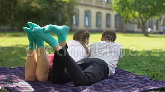 青少年的双腿穿着类似舒适的袜子躺在公园的格子布上纺织物视频的预览图