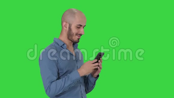 随意的阿拉伯商人使用电话和微笑的绿色屏幕铬钥匙视频的预览图