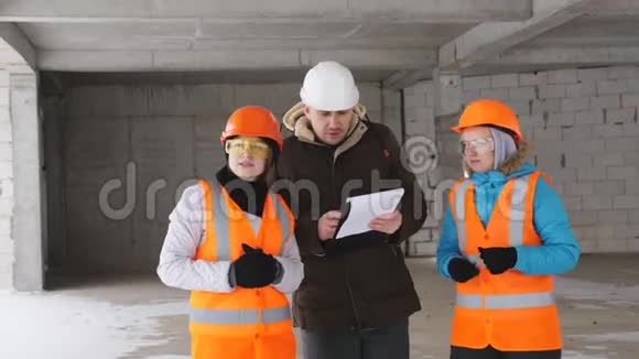 工头和两名妇女在冬季在工地上戴建筑头盔以检查建筑工人的状况视频的预览图