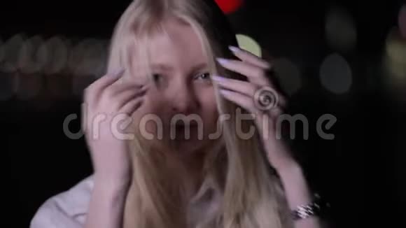 一位性感的金发女人在夜城摆着一头长发视频的预览图