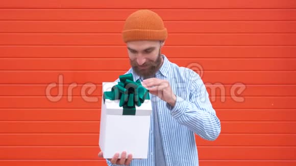 英俊的年轻臀部拿着红色背景的礼品盒节日和生日的概念视频的预览图