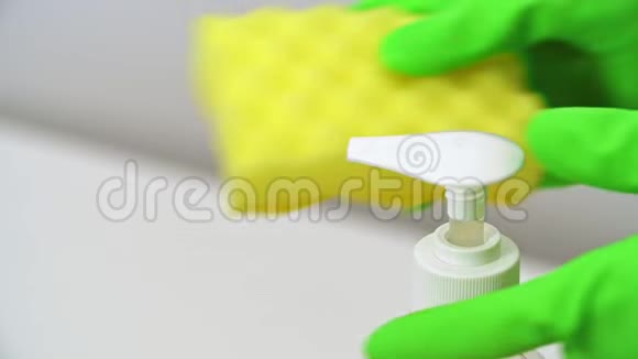 将绿色手套推式分配器和液体洗涤剂挤成黄色海绵视频的预览图