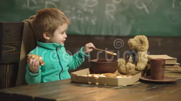在木制背景下吃披萨的男孩美味的披萨小男孩在吃披萨营养概念男孩视频的预览图