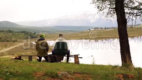 两个成年人的后景坐在长凳上花时间环顾山湖美景视频的预览图