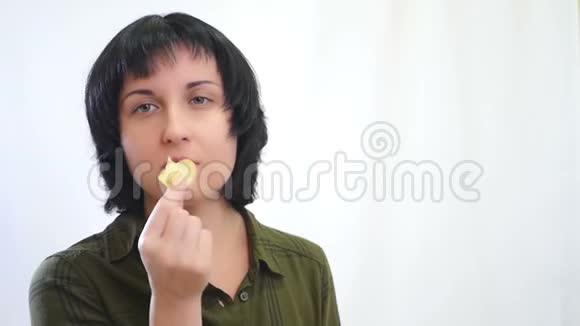 黑发女孩很高兴在白色背景下吃薯片视频的预览图