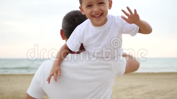 一个男人扛着他的肩膀一个快乐的笑着的男孩挥动他的手家庭和户外娱乐的概念视频的预览图