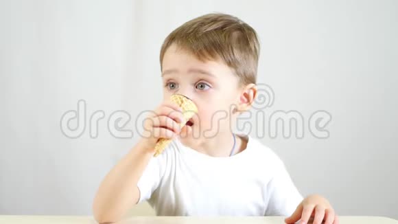 这孩子坐在一张桌子旁用华夫饼锥吃冰淇淋这个男孩喜欢吃美味的甜点视频的预览图