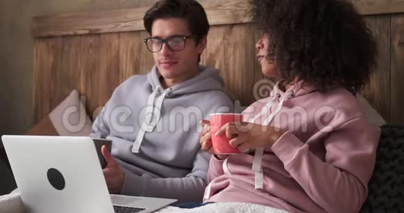 年轻夫妇在床上喝咖啡使用笔记本电脑视频的预览图
