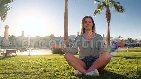 年轻的白种人女子通过在碧蓝潭青泥潭和莲花的草地上练习瑜伽来放松自己视频的预览图