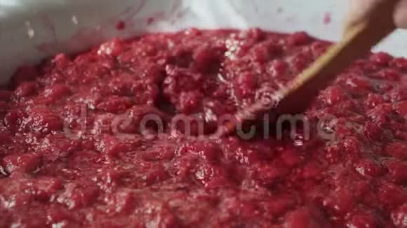 女人用木铲把树莓酱搅在漆包的碗里视频的预览图