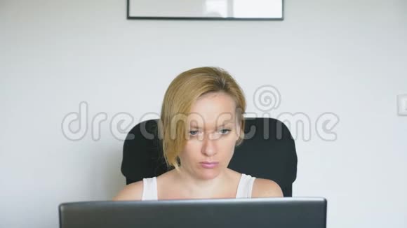 一个女人坐在桌子旁用她的笔记本电脑正经历着惊喜和喜悦人类的情感概念视频的预览图
