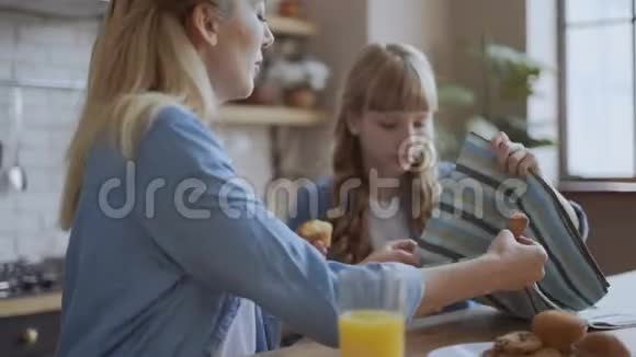 妈妈和女儿喝橙汁和饼干和松饼可爱的快乐家庭对话视频的预览图