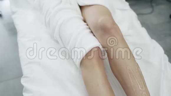 特写女性腿部涂有凝胶的白色桌子病人等待激光脱毛程序动作缓慢视频的预览图
