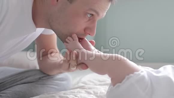 近距离拍摄父亲亲吻婴儿的脚视频的预览图