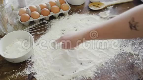 在厨房的餐桌上白色面粉上洒下的饼烘焙纸杯蛋糕的概念家庭烘焙手指书写单词视频的预览图
