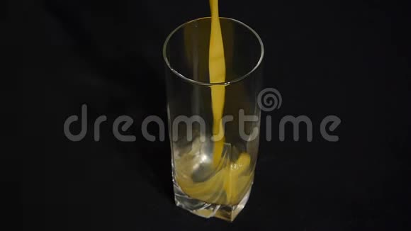 橙色或菠萝汁被倒入一个黑色背景的高玻璃中特写镜头有机饮料视频的预览图