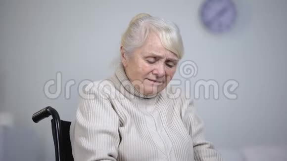轮椅上的老年妇女按摩膝关节疼痛健康问题视频的预览图