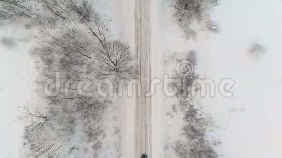 这辆车是黑色的车上挂着标志灯开着一条下雪的冬天的路树上光秃秃的树枝视频的预览图