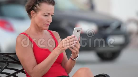 成熟快乐的旅游妇女坐在长凳上打电话视频的预览图