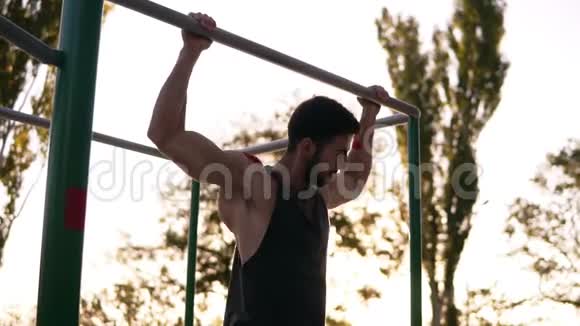 拔高力量训练运动健身者在户外健身房锻炼手臂肌肉做下巴上的拔高运动视频的预览图