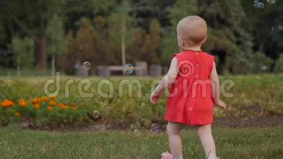 这个可爱的小女孩正在公园里的肥皂泡中奔跑视频的预览图