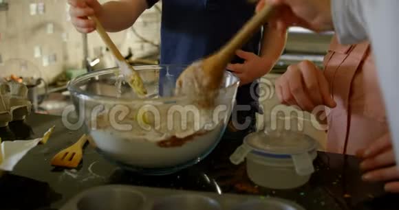 可爱的兄弟姐妹在厨房的碗里搅拌面团4k视频的预览图