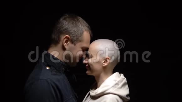 秃头的女人和她的丈夫在黑暗的背景下拥抱在一起复制空间视频的预览图