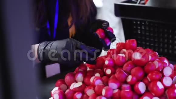 女人戴着黑色手套的手在整理一堆红色的萝卜视频的预览图