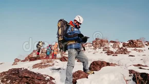 一个成年人和一个有经验的登山者和他的团队在一座雪山的边缘检查路线之前视频的预览图