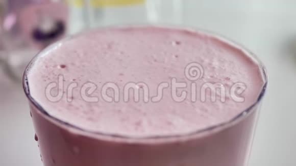 透明玻璃中的粉红色奶昔泡沫破裂特写自然光视频的预览图