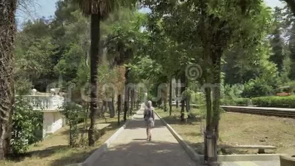 年轻女孩沿着棕榈巷走格鲁吉亚巴统植物园视频的预览图