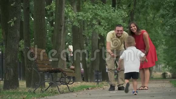 小男孩跑到公园里的父母那里视频的预览图