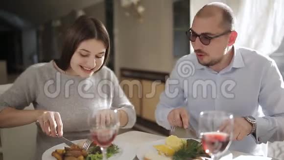 男人和女孩在舒适的餐厅吃晚饭两个人在餐厅的桌子上吃饭视频的预览图