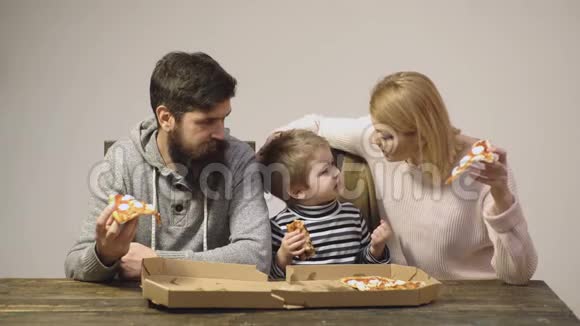 在木制背景下吃披萨的男孩美味的披萨营养概念一家人吃披萨的肖像快乐视频的预览图