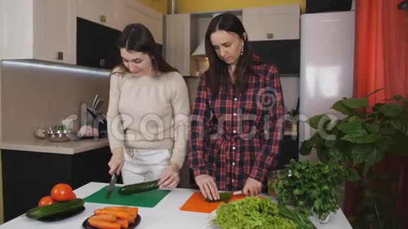 快乐的中年妇女和她的妹妹一起在现代烹饪健康食品时搅拌一碗新鲜沙拉视频的预览图