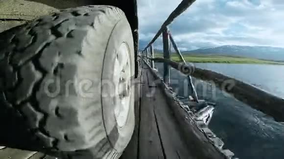 通过桥的汽车车轮的视图汽车旅行越野车骑在高山上的老木桥上视频的预览图