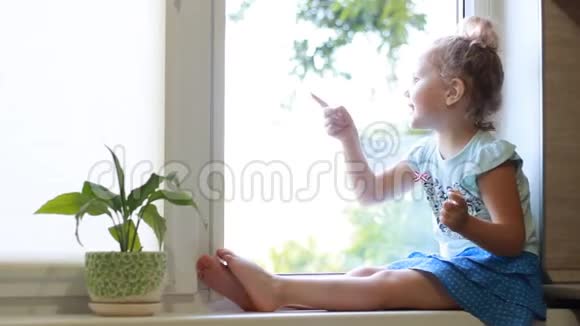 小女孩坐在窗台上向人们挥手视频的预览图
