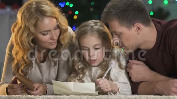 快乐的父母帮助可爱的女孩写信给圣诞老人相信奇迹视频的预览图