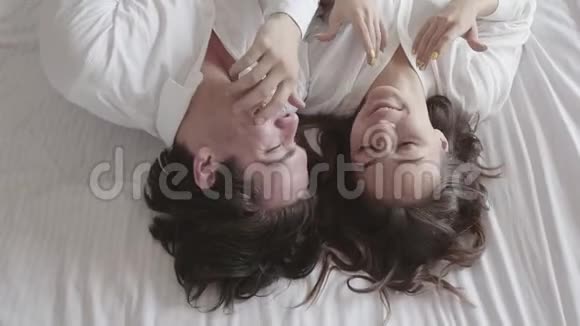 头顶射中幸福的年轻夫妇躺在床上谈特写俯视令人放松的男人和女人慢动作视频的预览图