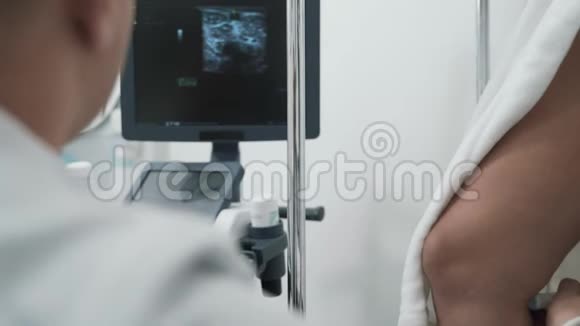 观点医生在病人腿上做超声波检查看着监视器闭上眼睛视频的预览图