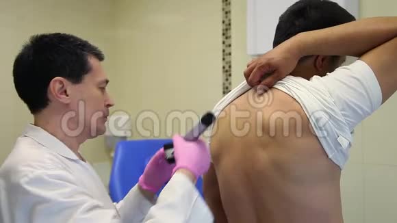 一位男医生用医疗电子设备检查病人皮肤视频的预览图