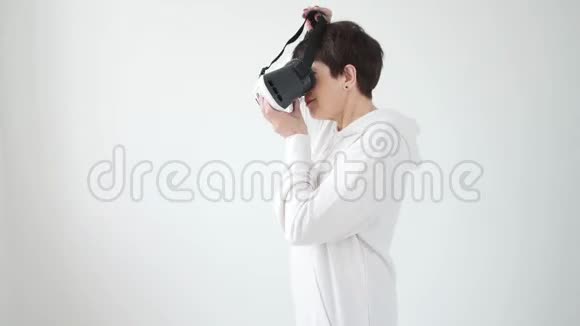 中年妇女穿着白色毛衣戴着虚拟现实眼镜看电影未来主义和新概念视频的预览图