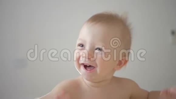 闭上宝宝的脸同时微笑和笑一个可爱的小宝宝正在看镜头视频的预览图