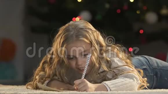 漂亮的女孩写信给圣诞老人用双手闭上眼睛想象礼物视频的预览图