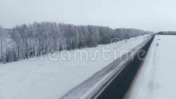 冬路雪田和雪林从上面射出在雪地里沿着一条狭窄的黑暗道路飞行视频的预览图