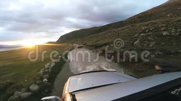 汽车旅行SUV在日落后在一条河上的高山道路上行驶POV汽车行驶的视角视频的预览图